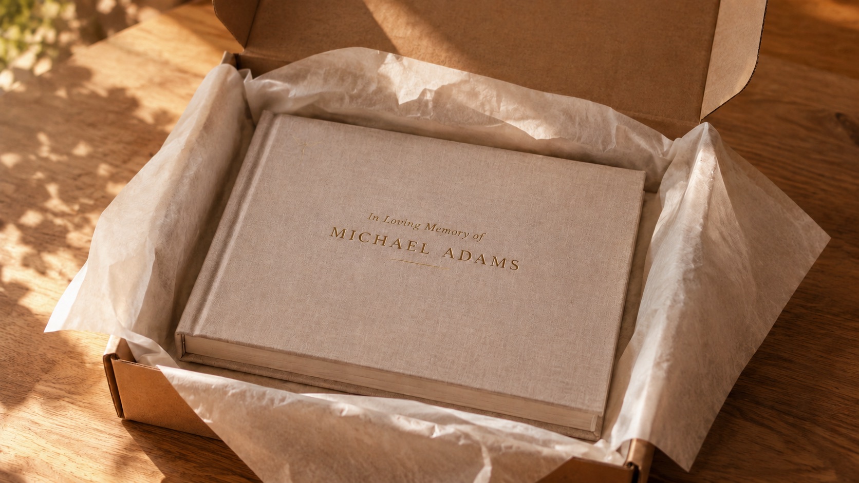 The finished hardcover half-drawn from its matching linen slipcase on a stone plinth in warm daylight, the name stamped in gold foil across cover and case — two artifacts, made to be kept.